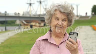 微笑的老年妇女展示<strong>银色手机</strong>